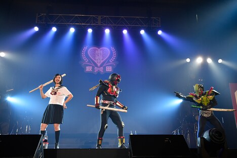 超神ネイガー（中央）と悪役を退治する小林歌穂（左）。（写真提供：SMEレコーズ）