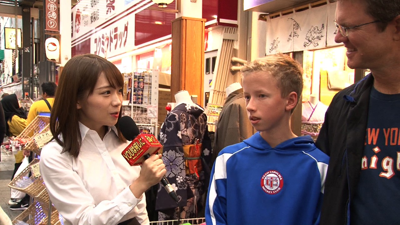 街中で外国人の子供にインタビューする秋元真夏（左）。(c)テレビ東京
