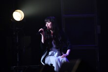 ステージ端に座ってお祝いコメントを観る南波志帆。