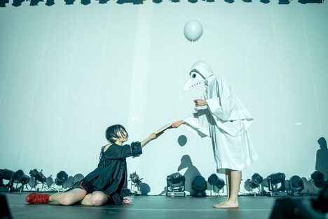 Maison book girl「Solitude Hotel 6F yoru」より、ペストマスクの人物から本を受け取る矢川葵。(撮影:稲垣謙一)