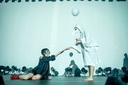 Maison book girl「Solitude Hotel 6F yoru」より、ペストマスクの人物から本を受け取る矢川葵。(撮影:稲垣謙一)