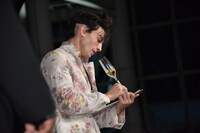 シャンパングラスのペンでメモを取るエズラ・ミラー。