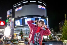 MV上映中の新宿ユニカビジョンを背に笑顔のLiSA。（Photo by Viola Kam[V'z Twinkle]）