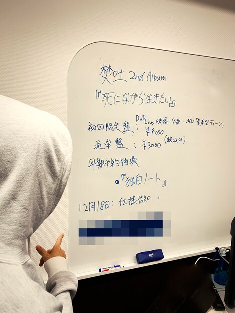 焚吐とアルバム「死にながら生きたい」の詳細が書かれたホワイトボード。