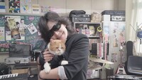 CM撮影時の様子。ふてニャンを抱いて笑顔のToshl。