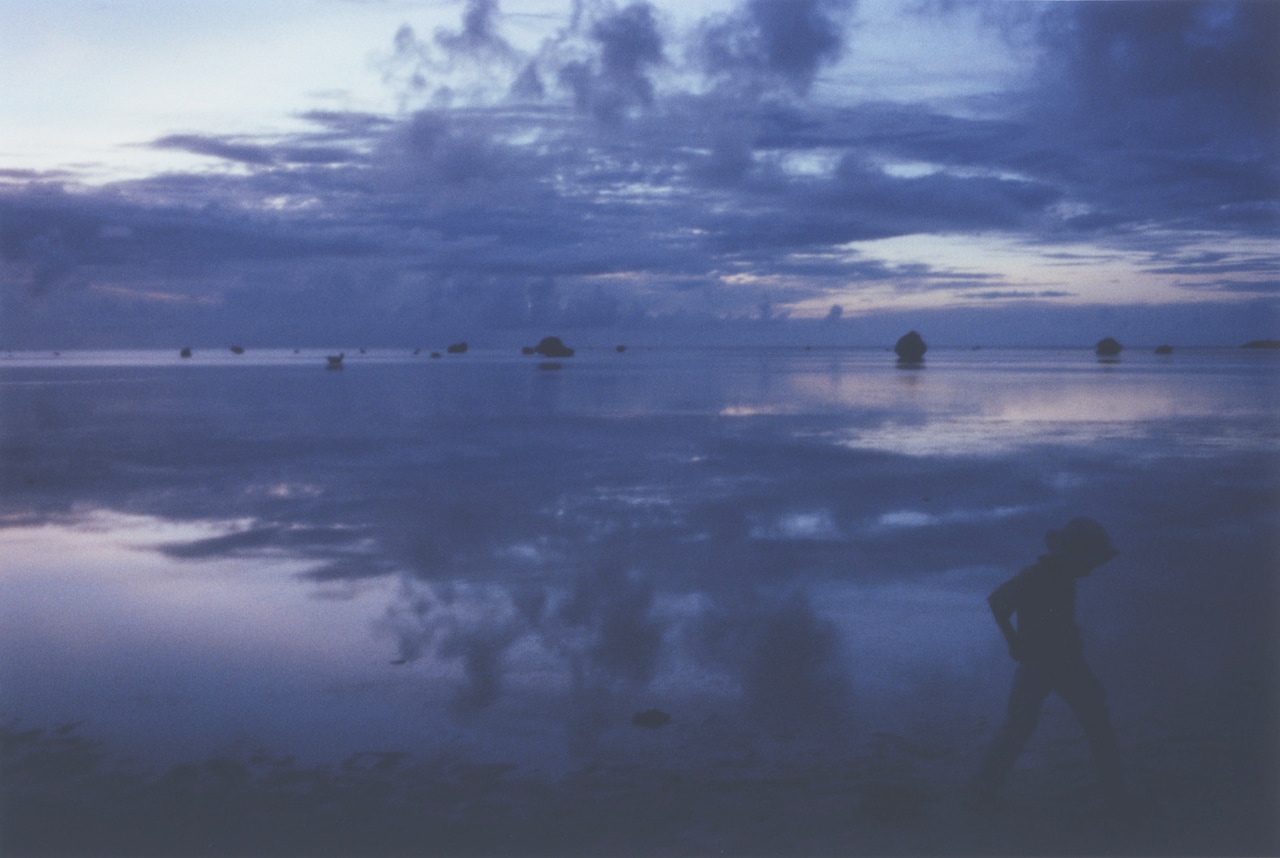 写真展「DEAR」より。空と波だけを写した作品郡の中で唯一、風景全景を写した。右下のシルエットは撮影旅行を共にした息子。2016年撮影。（写真提供：アミタマリ）