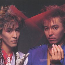 1984年デビュー当時の小室哲哉（左）と宇都宮隆。小室の風貌はCulture Clubのボーイ・ジョージを彷彿させる。（出典：「World Heritage」附録ブックレット / ソニーミュージックエンタテインメント）