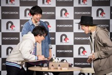 紙相撲で勝負する阿部敦と山田義孝（Vo）。（撮影：星野耕作）