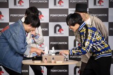 紙相撲で勝負する吉田結威（G, Vo）と寺島拓篤。（撮影：星野耕作）