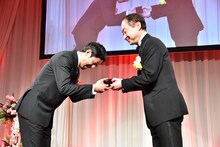 モノリスを受け取る濱津隆之（左）。