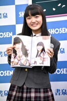 写真集のお気に入りのカットを見せる麻生真彩。