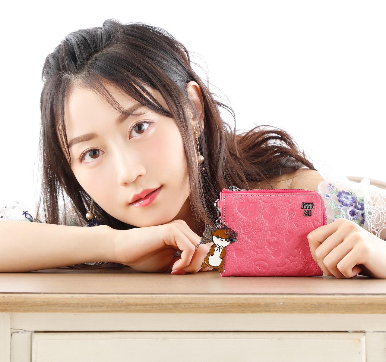 コラボアイテムのひとつ、牛革マルチウォレットを手にする小倉唯。