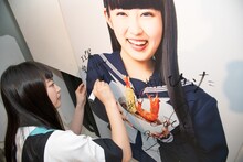 パネルにサインを書き入れる柏木ひなた。