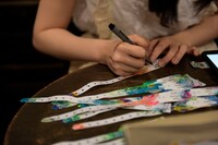 来場者のリストバンドに1つひとつ名前を記入していく湯木慧。（撮影：小嶋文子）