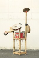 自作の日用品パーカッション。正面から見ると組み立て式のポール部分に目、鼻、口が描かれている。