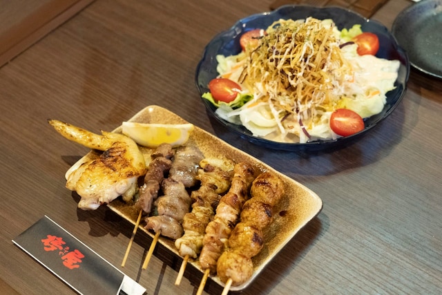 本格炭火焼鳥（1本150円～）と、さつま芋のパリパリサラダ（480円）。