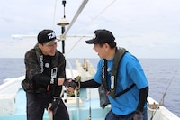 マグロを釣り上げて握手を交わす山下健二郎（左）、原西孝幸（右）。 (c)テレビ新広島