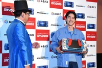 JOYSOUNDの社長（左）から「JOYSOUND MAX GO」をプレゼントされた菅田将暉。