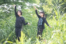 茂みに潜んで野鳥になりきる小林歌穂（左）と中山莉子（右）。