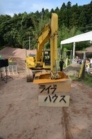 ライブハウスに見立てた小屋をユンボで破壊するまお。