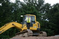 砂利山の上のユンボに立つまお。