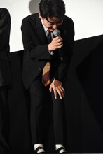 膝を抱えて笑う星野源。