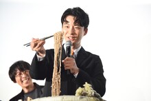 持ち上げた蕎麦を見つめる星野源。