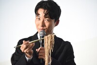 持ち上げた蕎麦を報道陣に見せる星野源。