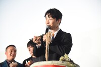 金色の箸で蕎麦を持ち上げる星野源。