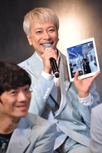 展示会場とスカパラメンバーをタブレットでつなぐ「スカパラの窓」の説明をする大森はじめ（奥）。