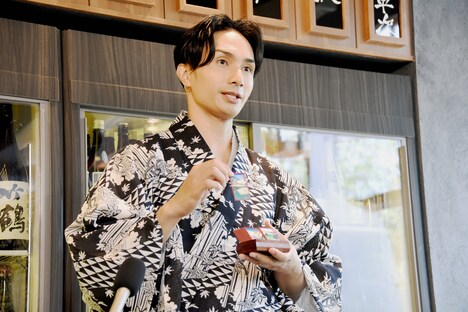 会計に用いる札を手にする橘ケンチ。札には江戸時代の目黒の風景が描かれている。