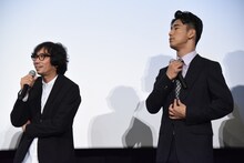 行定勲監督（左）が小林直己（右）の“首の太さ”について語る背後で襟元を整える小林直己。