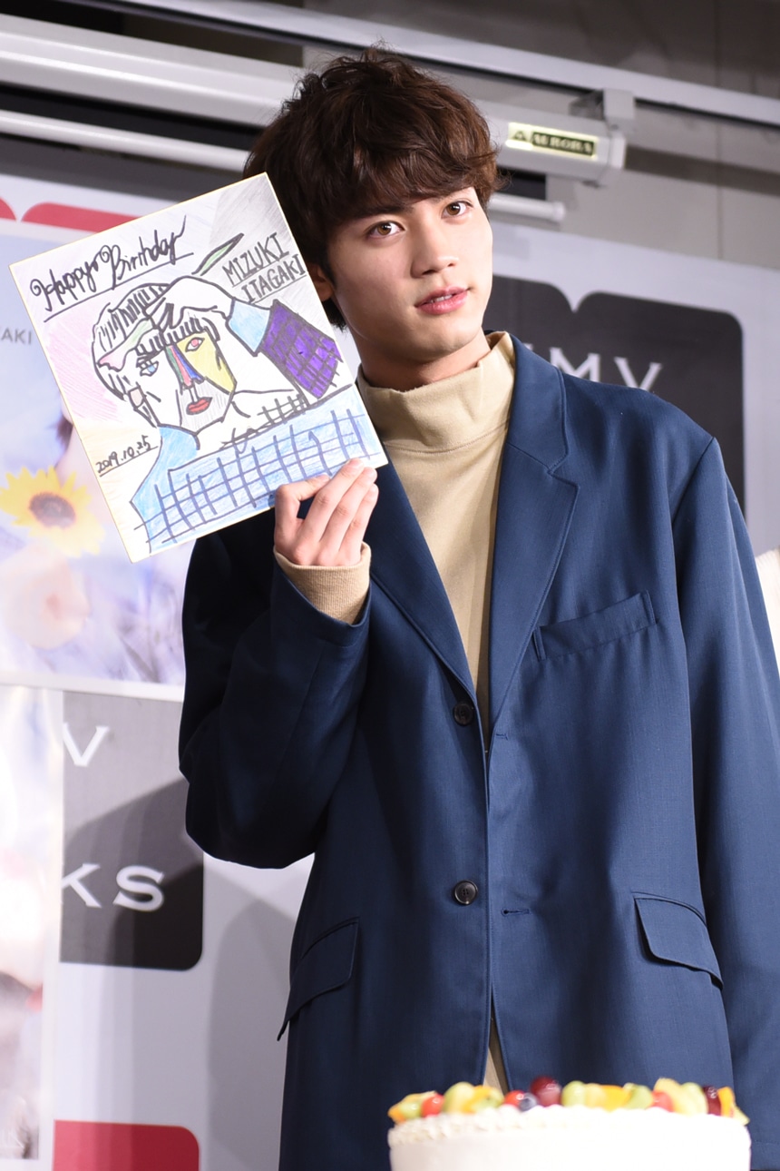 似顔絵を顔の横に並べる板垣瑞生。