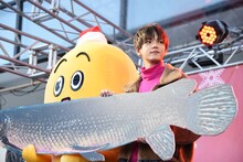 アリゲーターガーの実物大パネルを持つナナナと中島颯太。