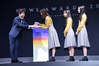トロフィーを受け取る日向坂46の3人。