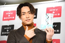 「三つ編みライフ ～夢を叶えた31の言葉～」をカメラにアピールするEXILE TETSUYA。
