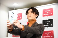 「三つ編みライフ ～夢を叶えた31の言葉～」をカメラにアピールするEXILE TETSUYA。