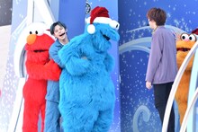 エルモとクッキーモンスターに挟まれるカイと、それを見るリョウガ（右）。(c)2019 Sesame Workshop