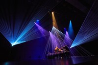 ベッドに座ってグランドピアノを弾くまらしぃ。（Photo by Daisuke Ishizaka）