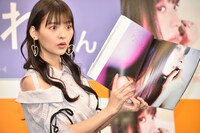 記者から写真集の持ち方をリクエストされ目を見開く上坂すみれ。