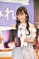 記者からしっかり開くようにリクエストされ写真集を左右に引っ張る上坂すみれ。