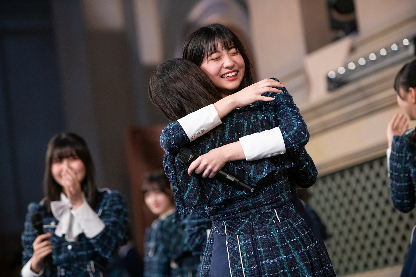 歌う前に感極まって涙する学級委員・日比野芽奈に抱きつく兼行凜。