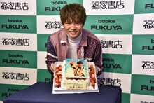 「STEP BY STEP」表紙がデザインされたバースデーケーキと佐藤大樹。