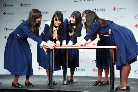 協力してフラッグにサインをする5人。