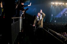 キックボードに乗りファンに挨拶する岡崎体育。