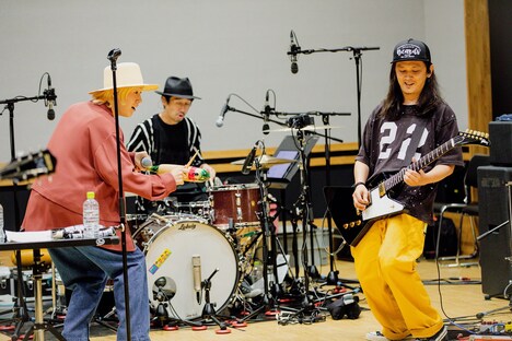 ギロを手にしてバンドメンバーの演奏に加わる山田義孝（Vo）。（撮影：白石達也）