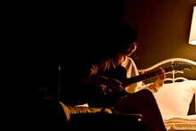 ベッドに腰掛けて歌う宮崎朝子。（撮影：河上良）