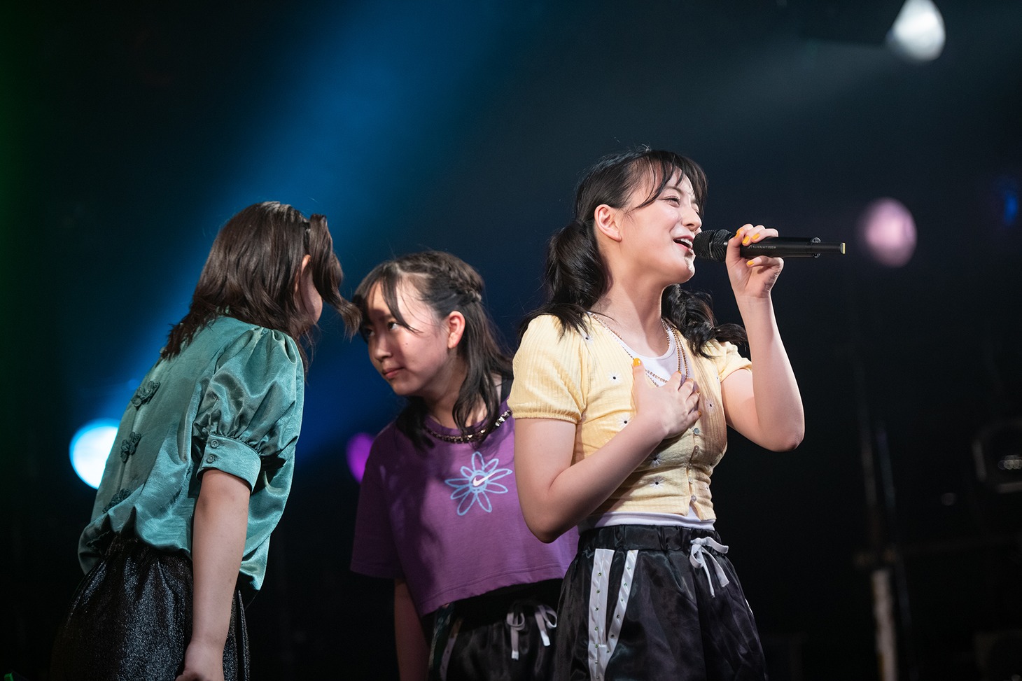 歌う清井咲希（右）の後ろで見つめ合う根岸可蓮（左）と堀くるみ（中央）。