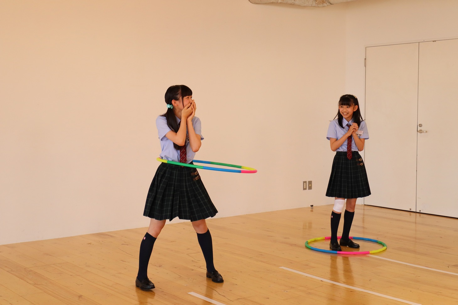 フラフープを回し続ける佐藤愛桜（左）と早々に落としてしまった野崎結愛。（写真提供：アミューズ）