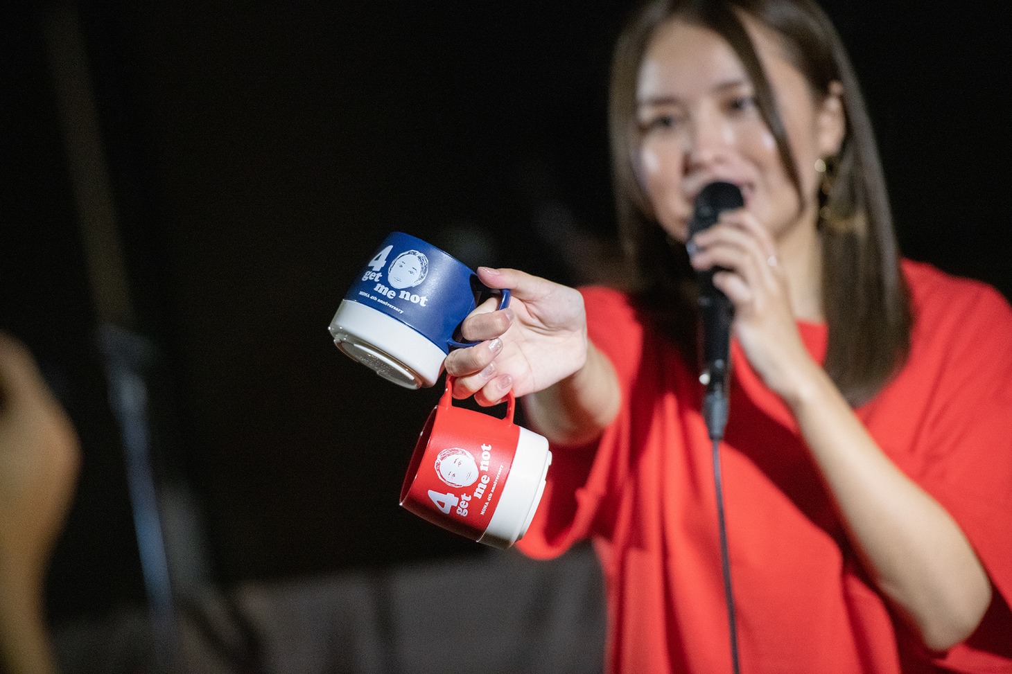 4周年ライブの記念グッズ、DINEXマグカップを紹介する脇田もなり。